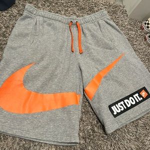 COPY - Grey Nike shorts with an orange swoosh on front and one pocket on the ba…